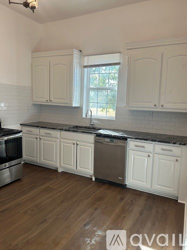 A kitchen with white cabinets and wooden floors.