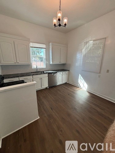 A kitchen with white cabinets and a wooden floor.