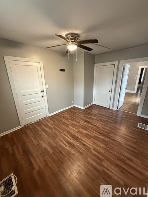 A room with a ceiling fan and wooden flooring.