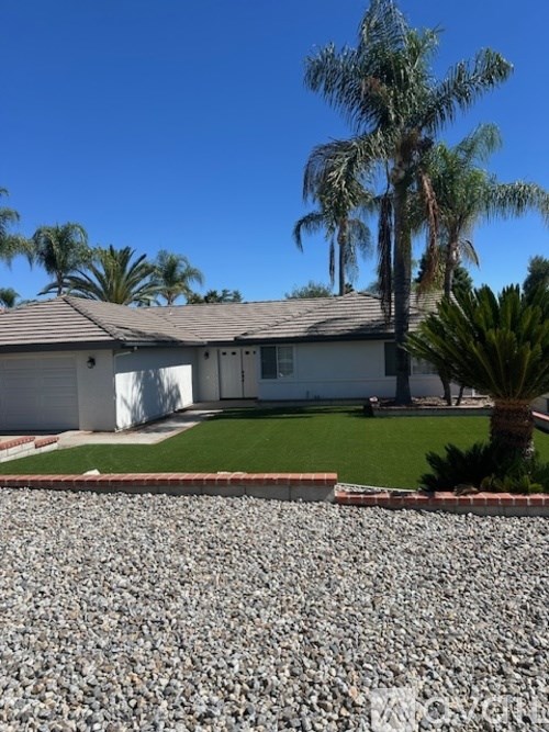 A house with a grey roof and a gravel driveway in front.