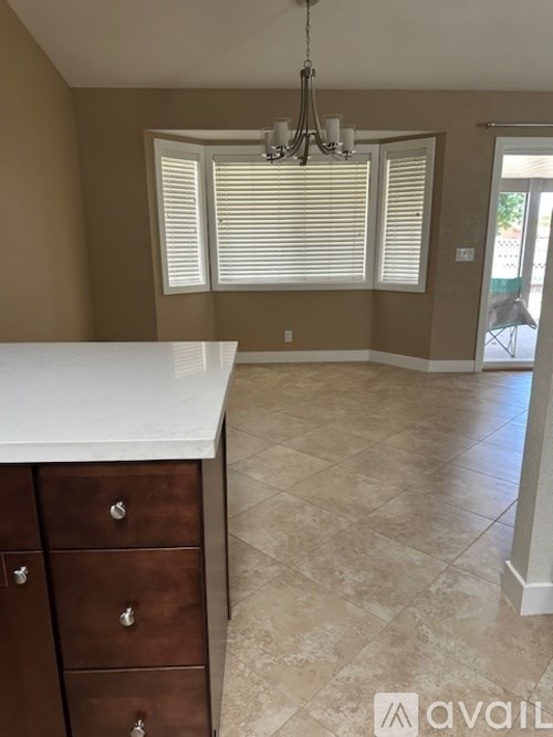 A kitchen with a white counter top and brown drawers.