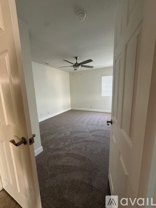A room with a ceiling fan and carpeted floor.