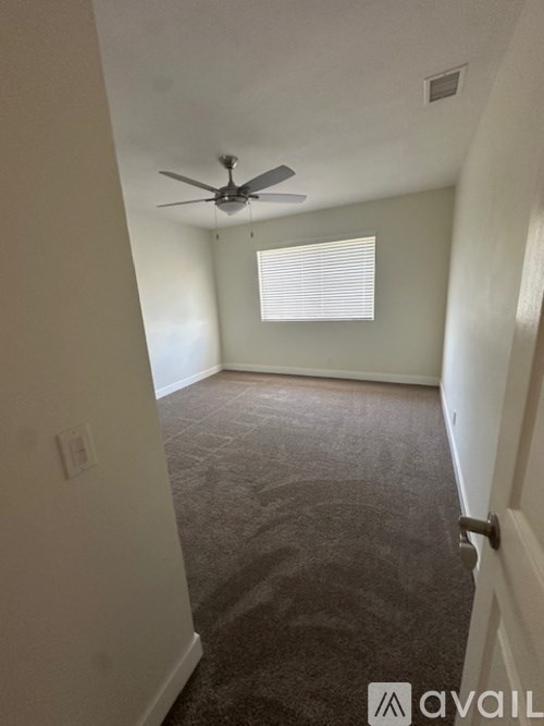 A room with a ceiling fan and carpeted floor.