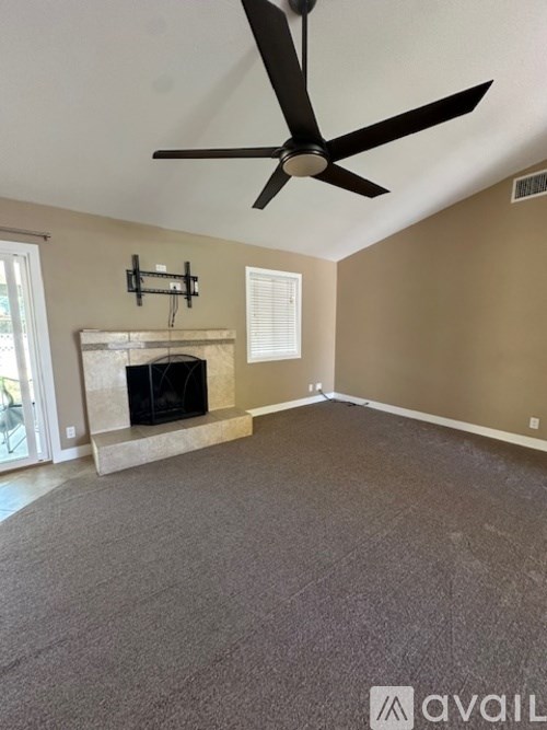 A living room with a fireplace and a ceiling fan.