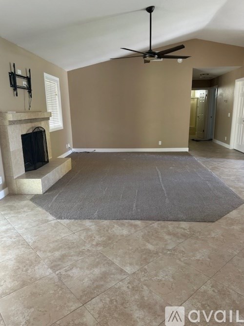 A living room with a fireplace and a ceiling fan.