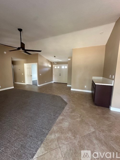 A spacious room with a ceiling fan and a rug on the floor.