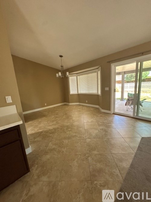 A spacious room with tiled flooring and a sliding glass door leading outside.