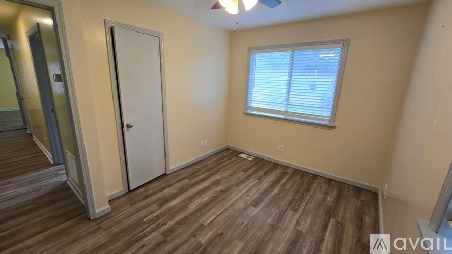 A room with wooden flooring and a window with blinds.