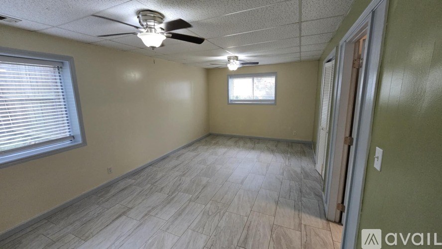 A room with a ceiling fan and a window with blinds.
