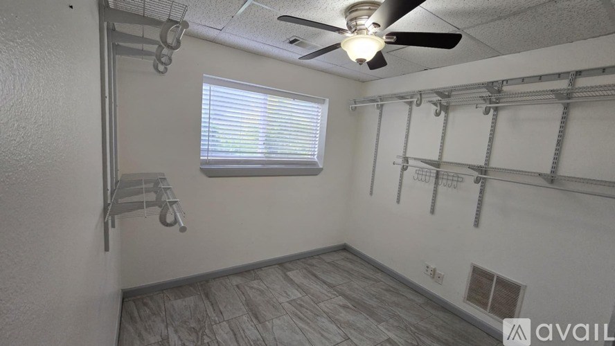 A room with a ceiling fan and a window with blinds.