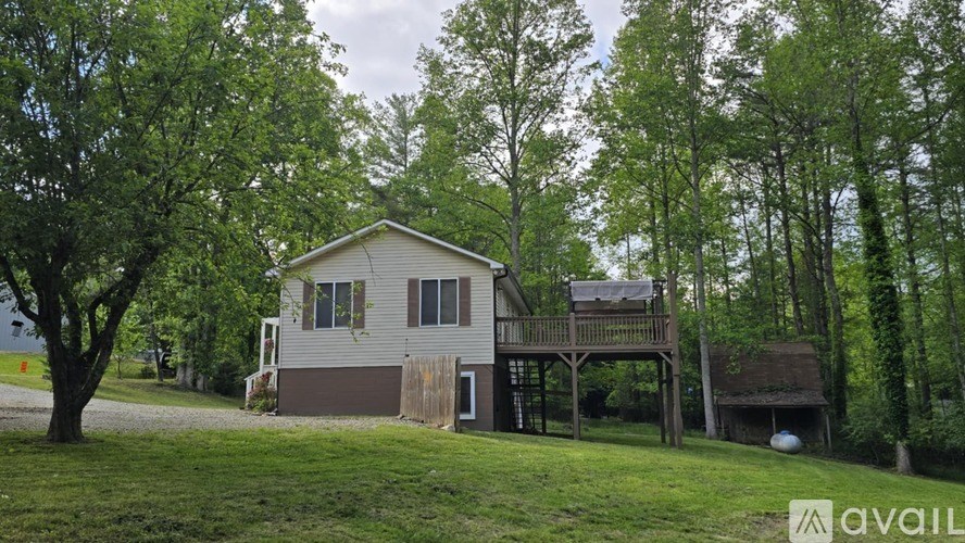 A house with a deck is surrounded by trees and grass.
