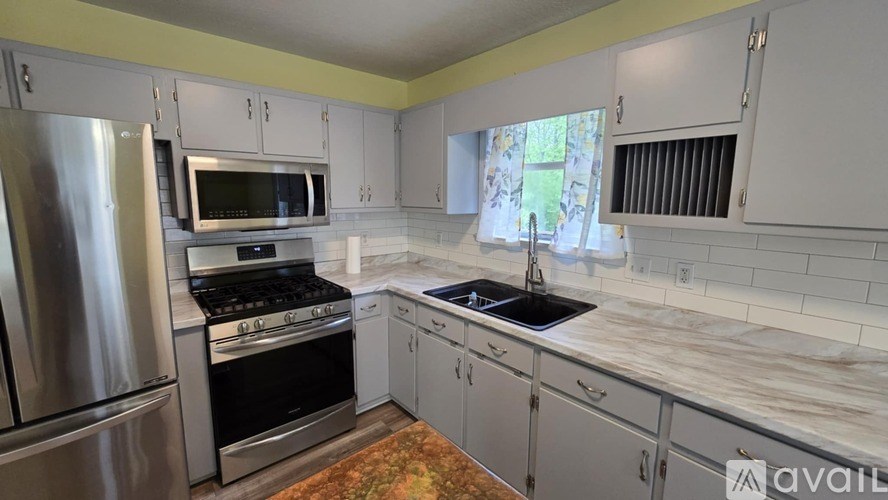 A kitchen with a stainless steel refrigerator, oven, and sink.