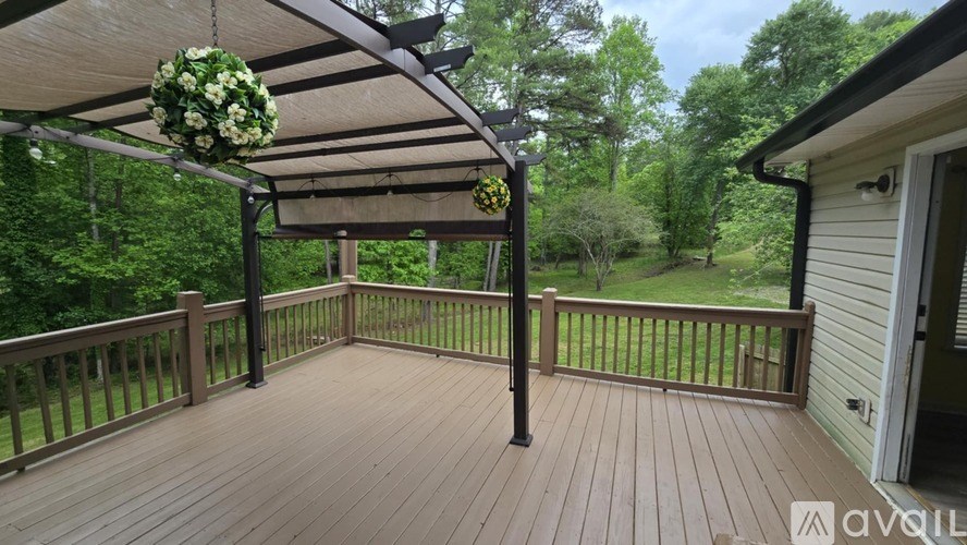 A wooden deck with a pergola and a hanging flower arrangement.