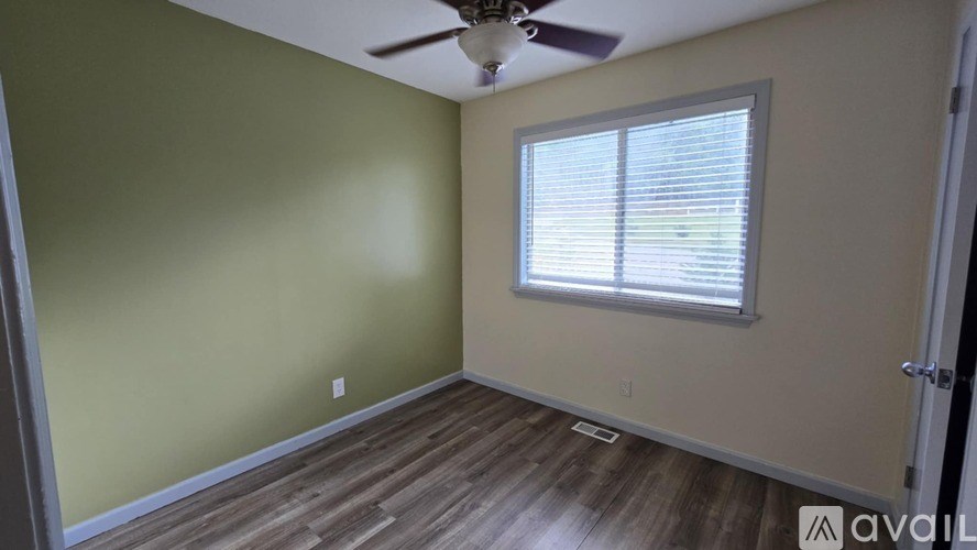 A room with a ceiling fan and a window with blinds.