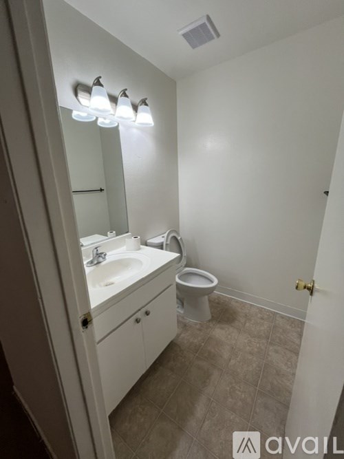 A bathroom with a toilet, sink, and mirror.