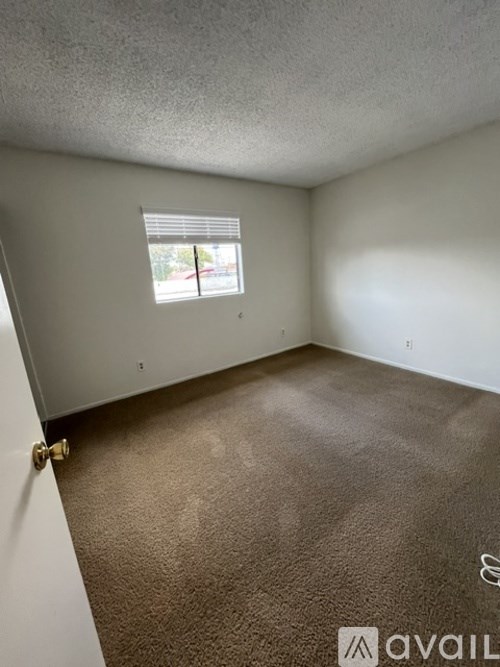 A room with a carpeted floor and a window with blinds.
