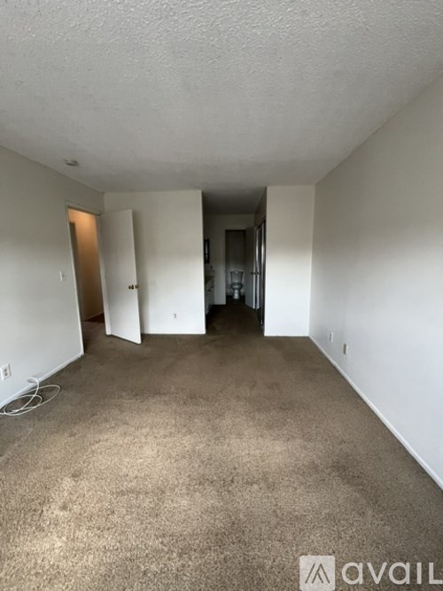 A carpeted room with a doorway leading to another room.