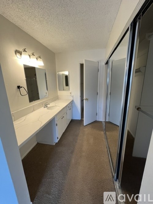 A bathroom with a sink, mirror, and shower.