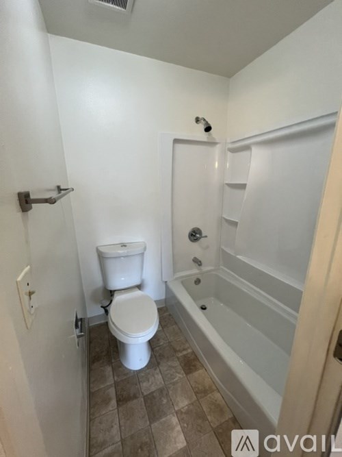 A white toilet sits in a bathroom next to a bathtub.