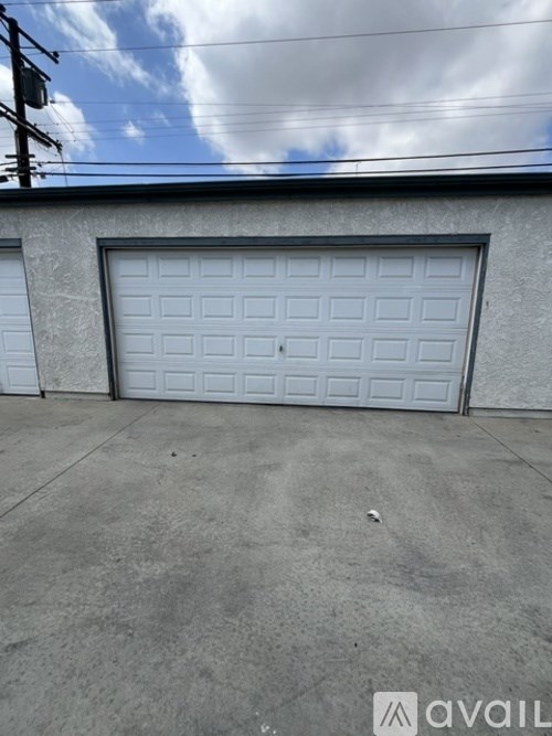 A white garage door is closed and the wall is grey.