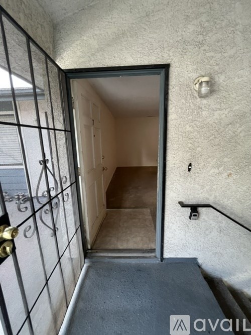 A black metal gate with a gold handle is on the left side of a doorway leading to a hallway.