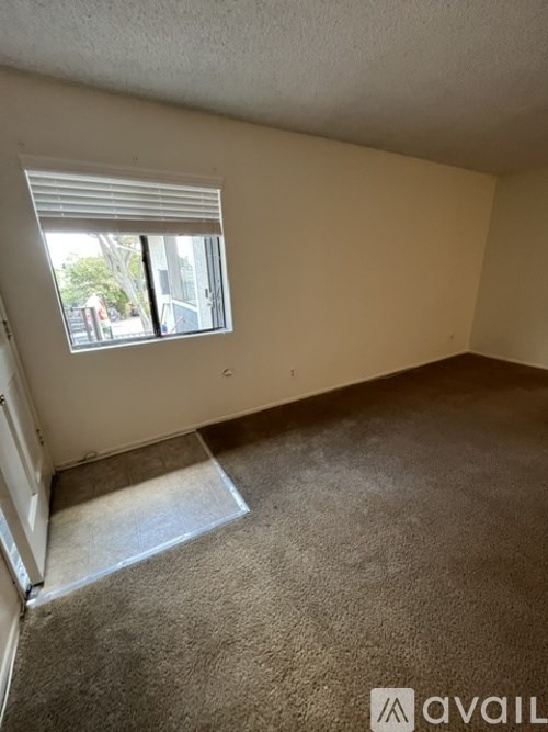A room with a carpeted floor and a window with blinds.