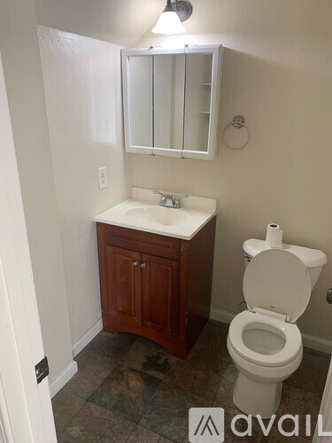 A bathroom with a toilet, sink and medicine cabinet.