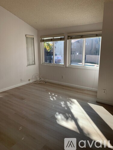 A room with wooden floors and a window with blinds.