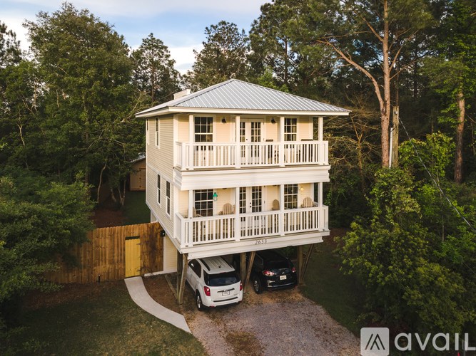 A house with a balcony and a car parked in front.
