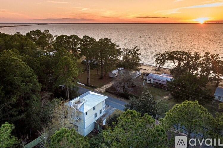 A house is surrounded by trees and is located near a body of water.