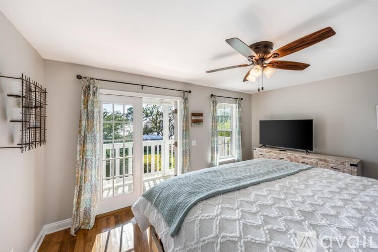 A bedroom with a bed, a ceiling fan, and a television.
