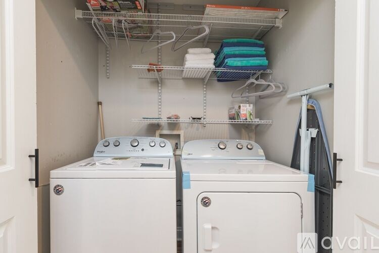A small laundry room with two washing machines and a shelf above them.