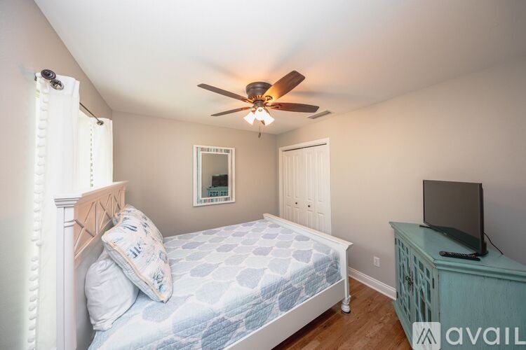 A bedroom with a bed, a dresser, and a ceiling fan.