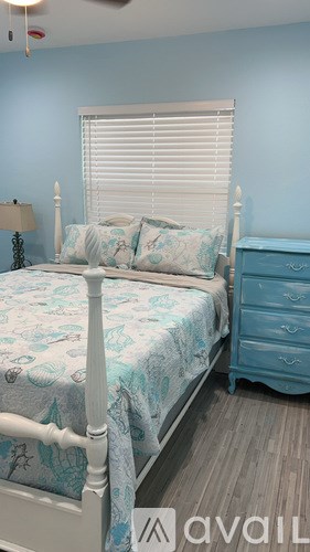 A bedroom with a bed, dresser, and window with blinds.