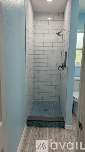 A bathroom with a blue shower stall and a wooden floor.