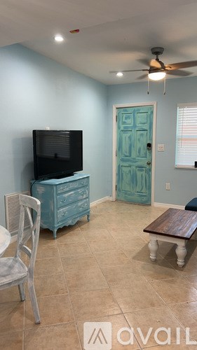 A room with a television, chair, and a dresser.