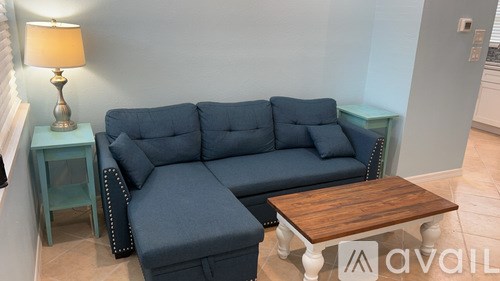 A living room with a grey couch, a wooden table, and a lamp.