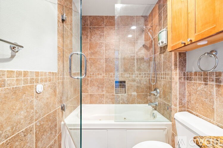 A bathroom with a glass shower door and a white bathtub.