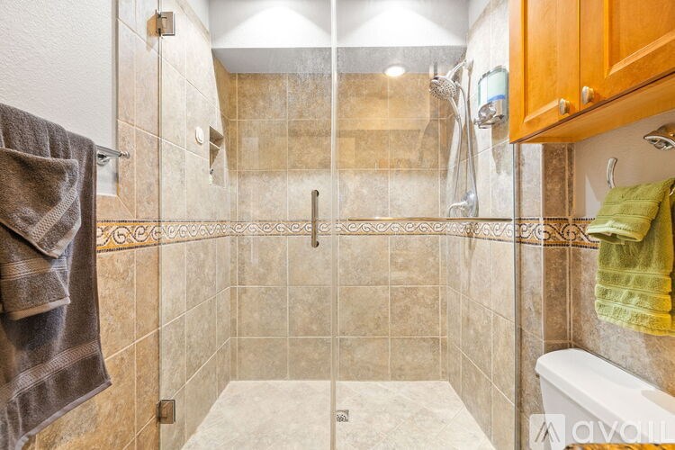 A bathroom with a walk-in shower and a towel hanging on the wall.