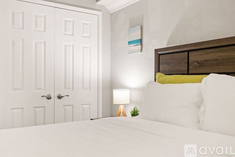 A bedroom with a bed, a lamp, and a painting on the wall.