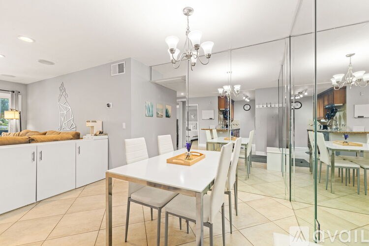 A dining room with a table and chairs and a kitchen area in the background.
