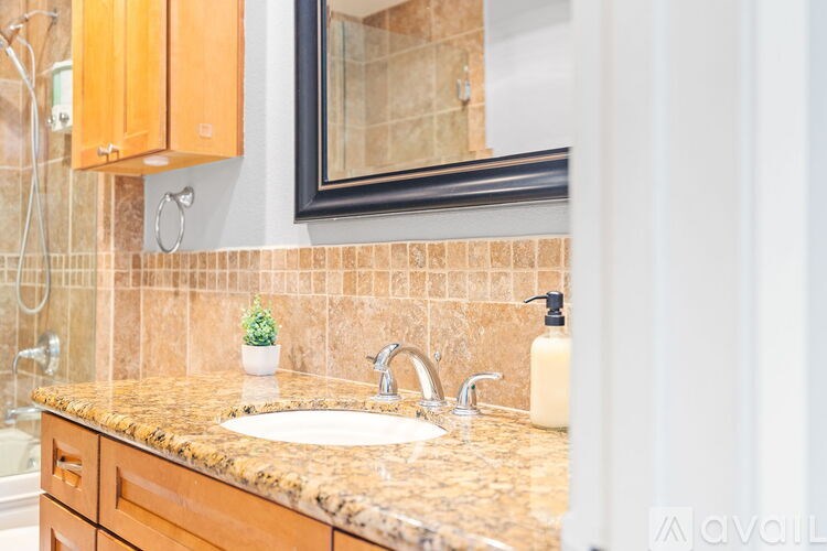 A bathroom with a brown granite countertop and a white sink.