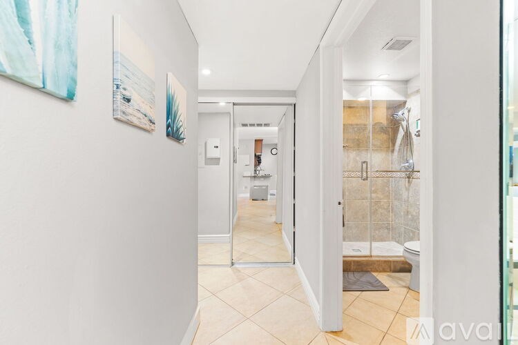 A hallway with a glass door leading to a bathroom.