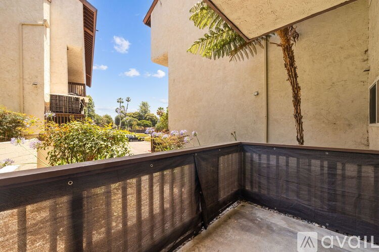 A balcony with a black railing and a view of a building and trees.