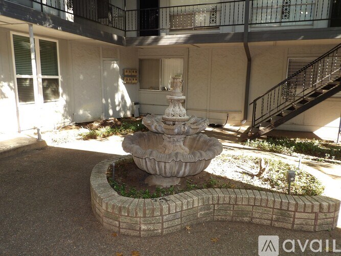 A fountain in a courtyard surrounded by a brick wall.