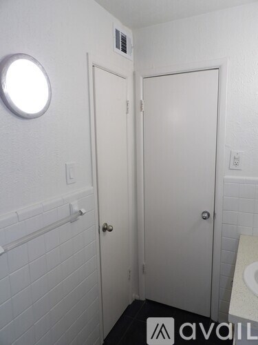 A bathroom with a toilet, sink, and a round window.