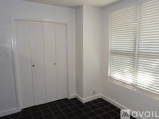 A room with a black tile floor and a window with blinds.