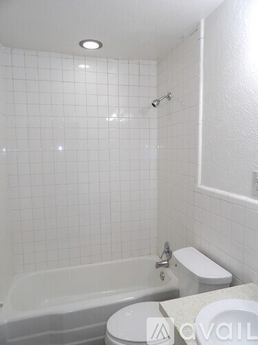 A white bathroom with a tub, toilet and sink.