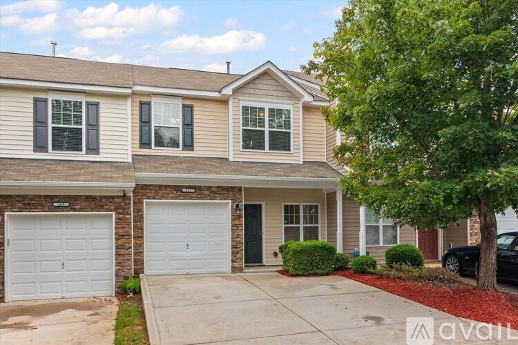 A two-story house with a garage and a tree in front.
