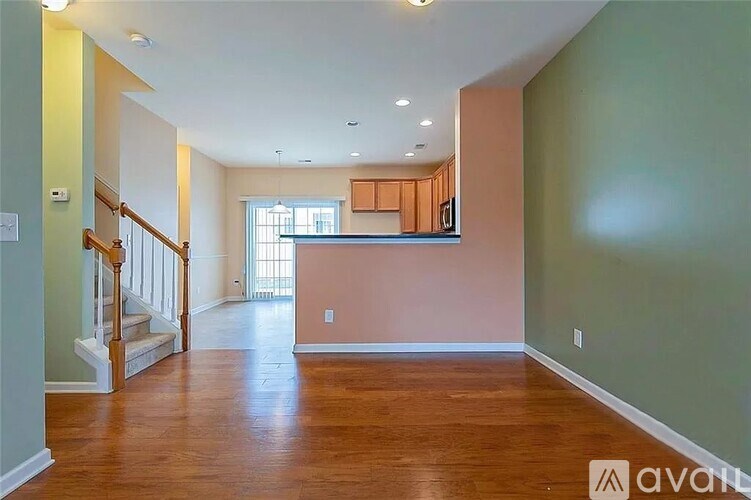 A spacious living room with wood flooring and a staircase on the left side.